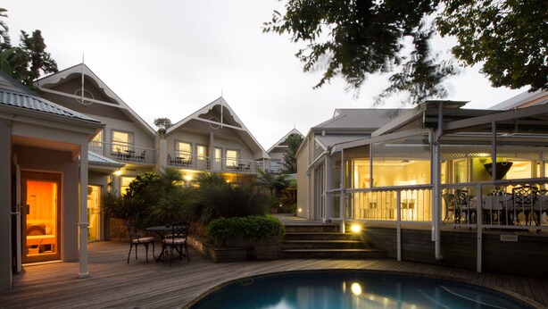 A pool area with a wooden deck, a lounge chair, and a covered seating area with tables and chairs. - Quarry Lake Inn (East London)