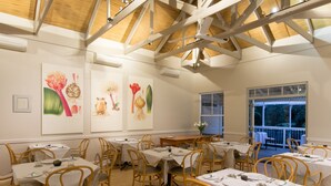 A dining area with tables set for guests, wooden chairs, and ceiling fans. - Quarry Lake Inn (East London)