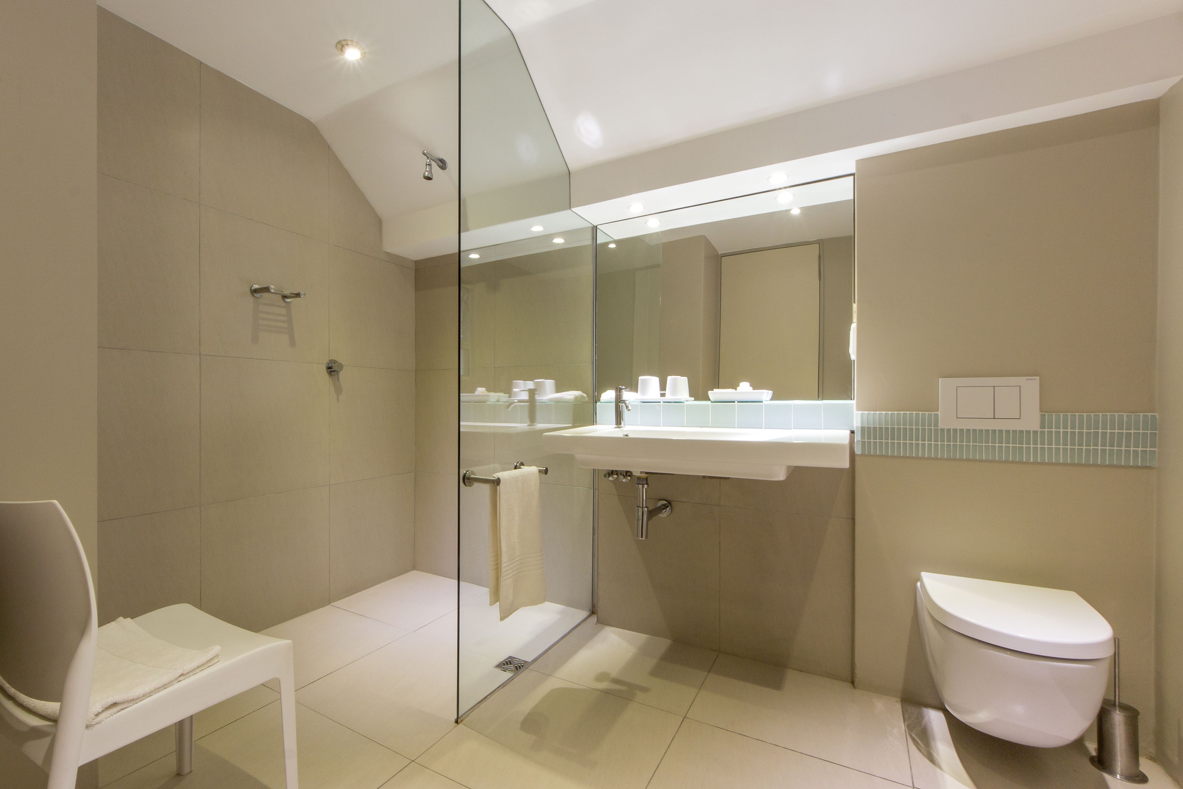 A modern bathroom with a glass shower enclosure, a white sink, and a toilet.