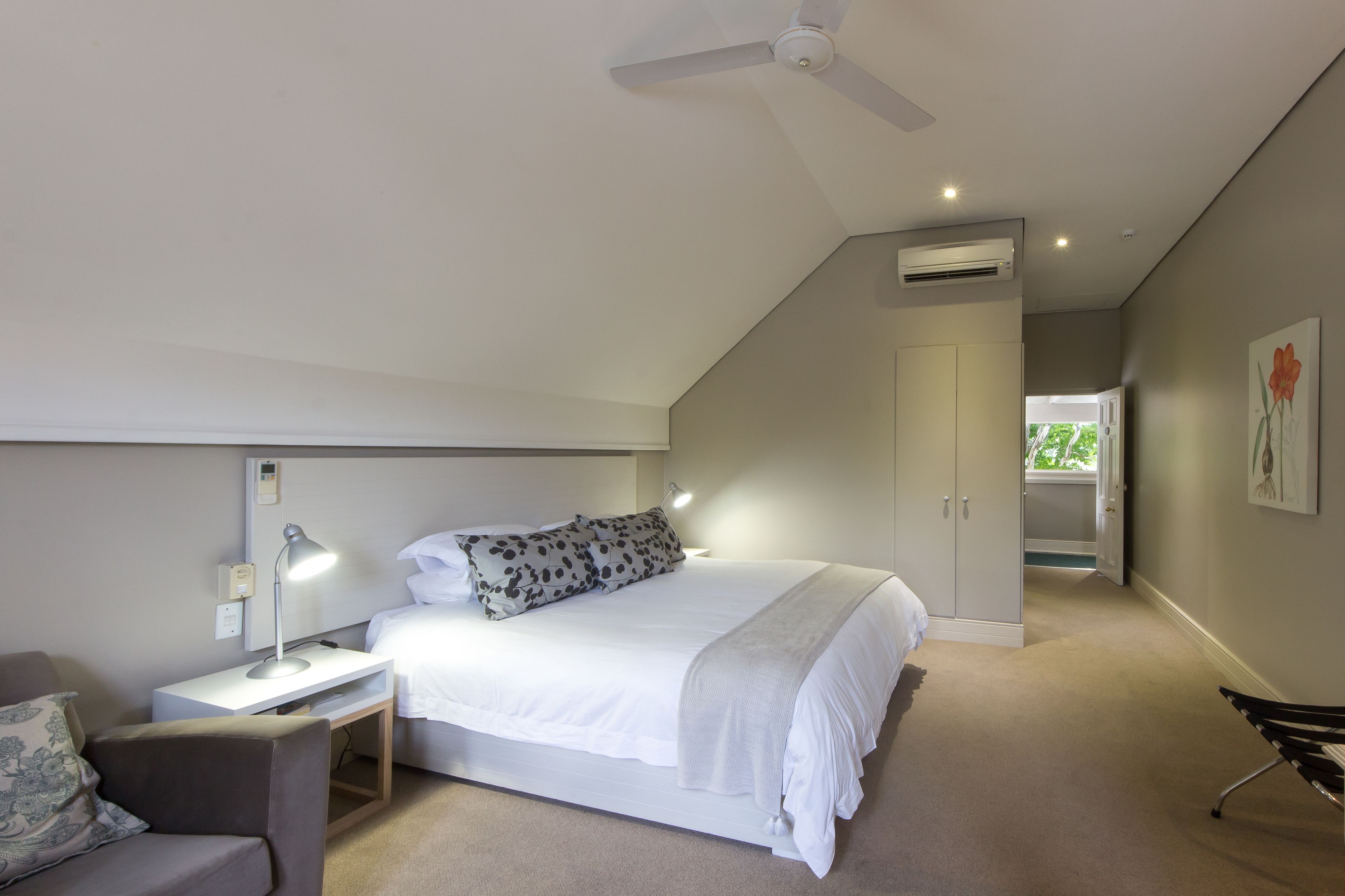 A bedroom with a bed, bedside table, lamp, and a ceiling fan.