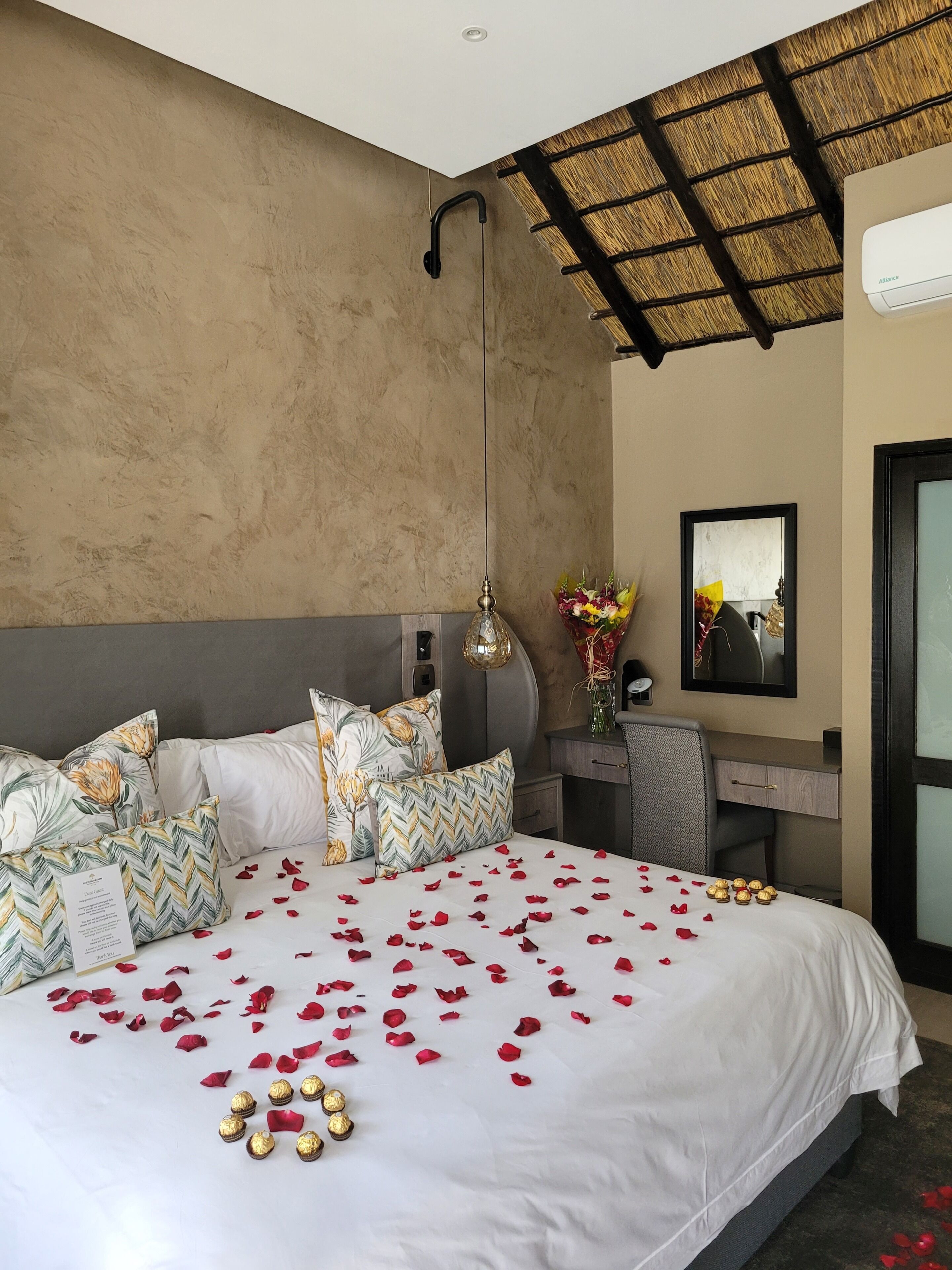 Une chambre d’hôtel avec un grand lit, un bureau, un miroir et un ventilateur de plafond.