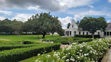 A white building with a dome, surrounded by well-manicured gardens and trees.
