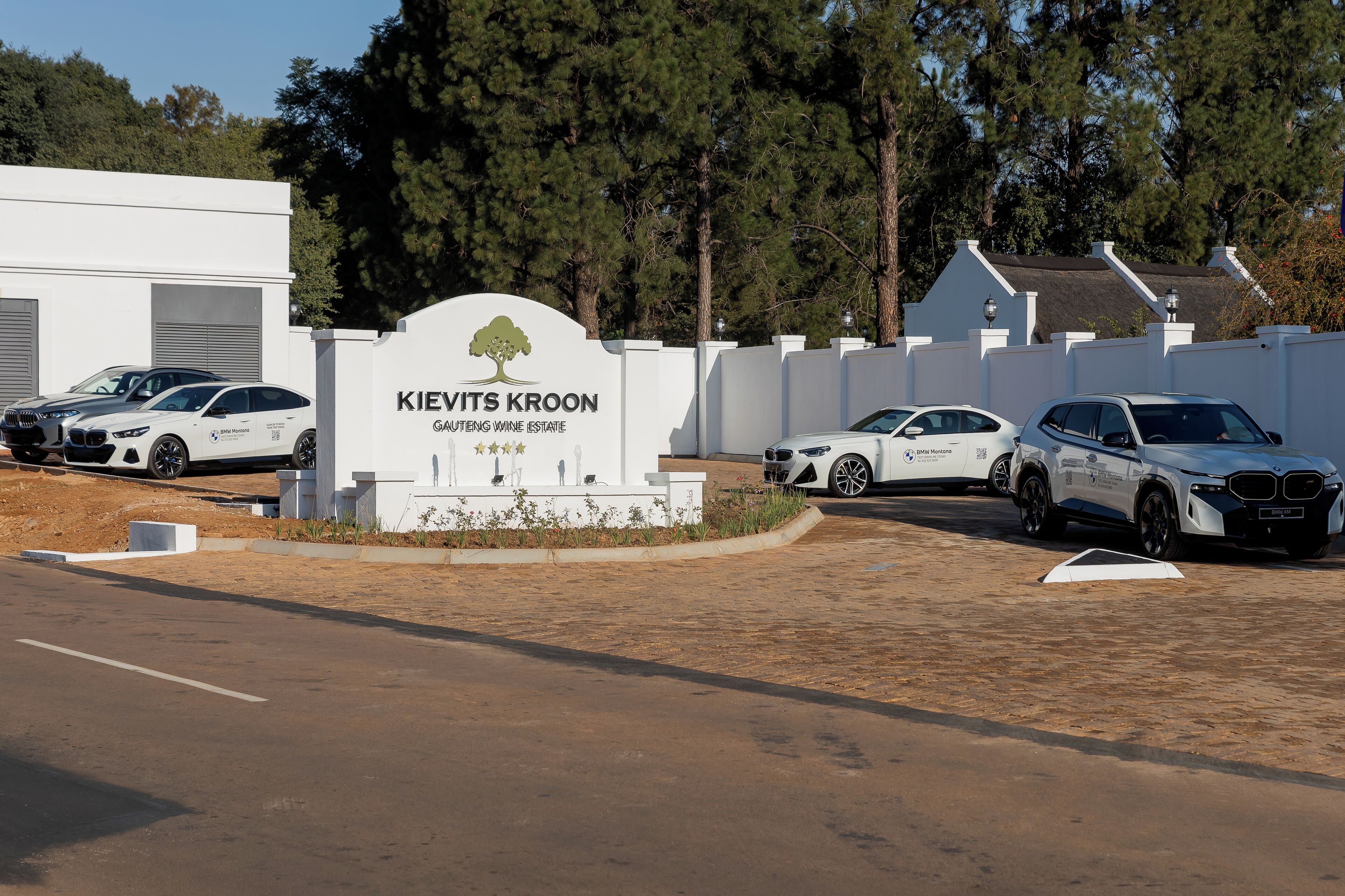 A sign for Kiewits Kroon with a BMW car parked in front.