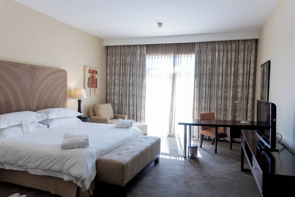 Una habitación de hotel con una cama grande, un escritorio, una silla y una televisión.