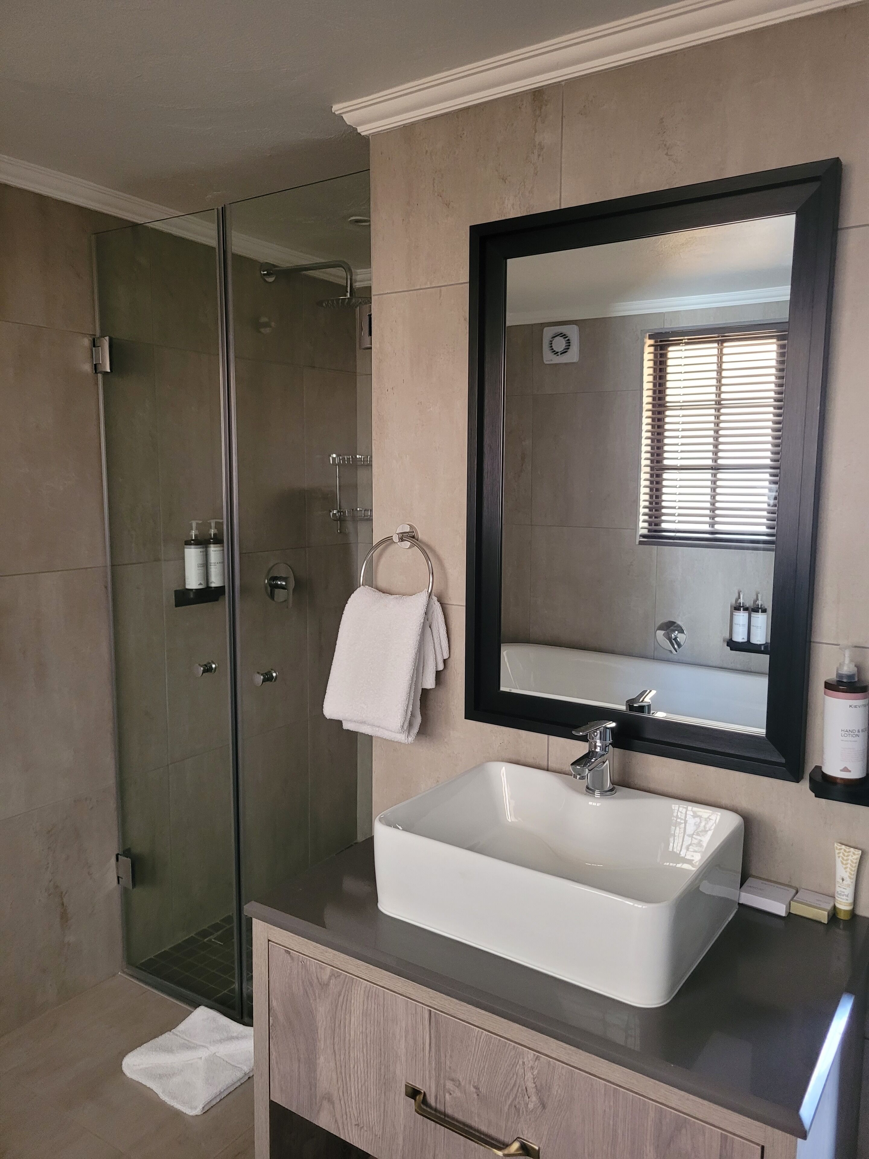 Un baño moderno con cabina de ducha de vidrio, un lavabo blanco y un espejo grande.