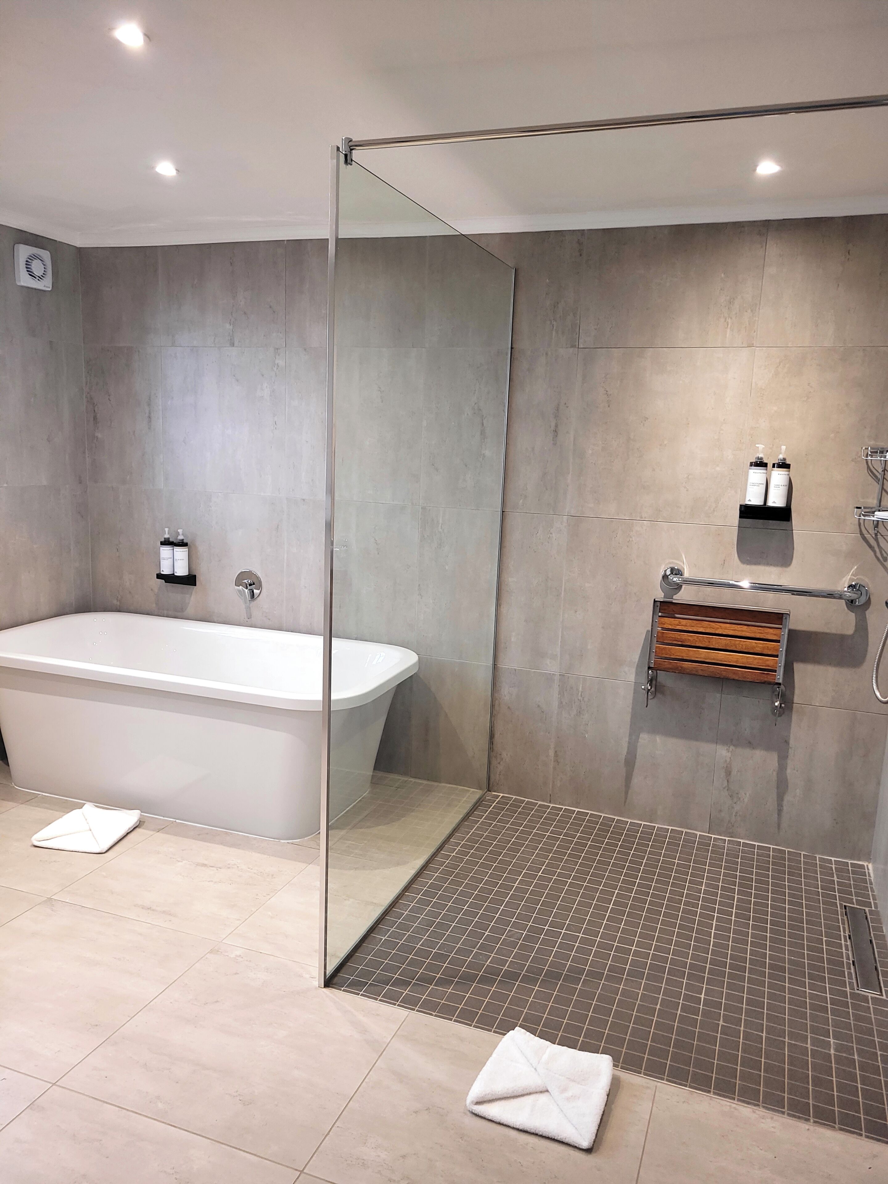 Un baño moderno con una bañera independiente, cabina de ducha con vidrio y suelo de baldosas.