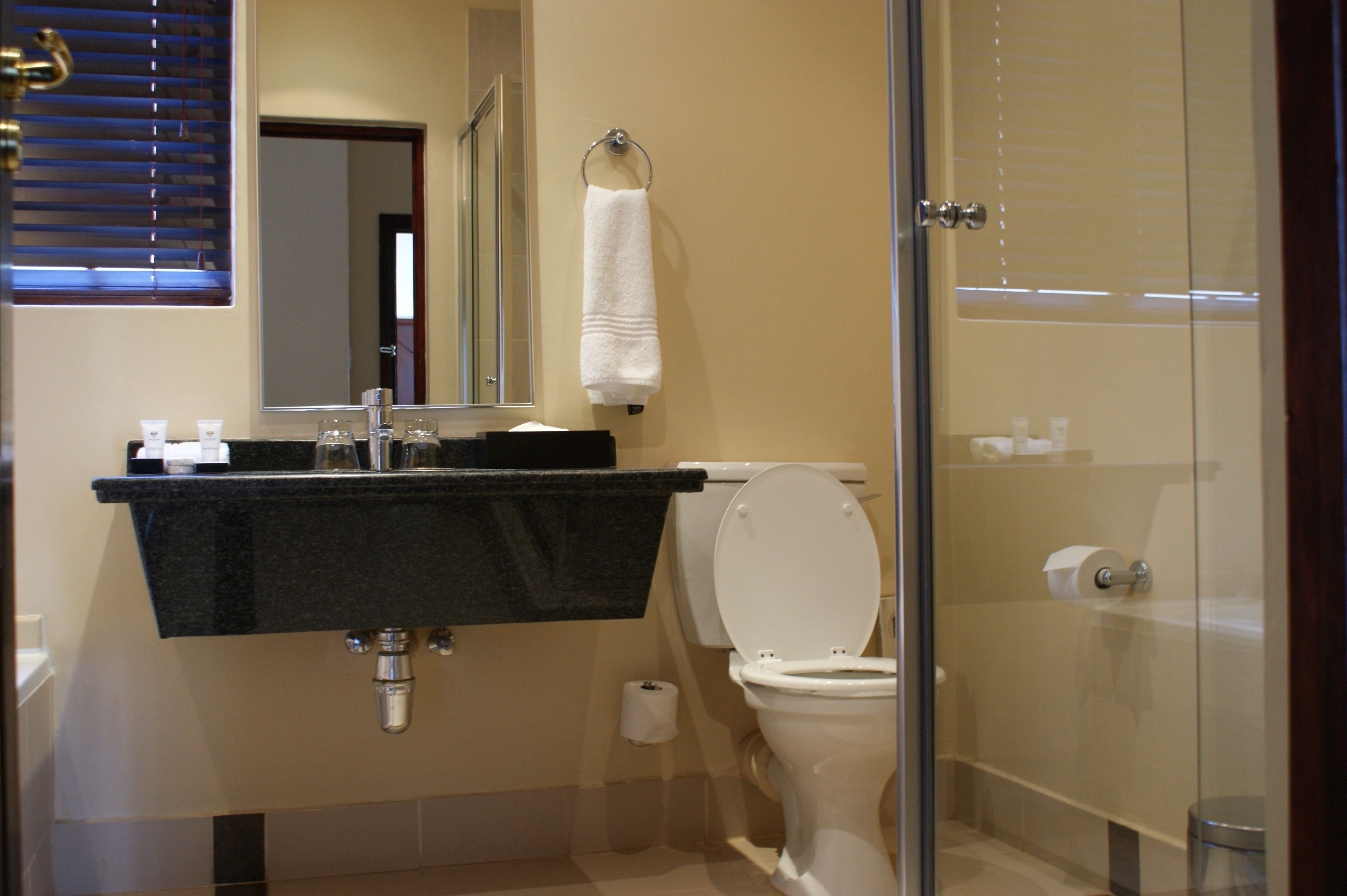 Un baño con lavabo, espejo, inodoro y cabina de ducha de vidrio.
