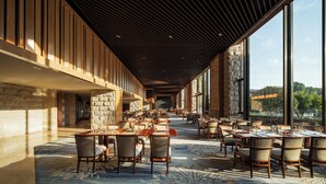 Un restaurante espacioso con techos altos, ventanas amplias y vistas al exterior.