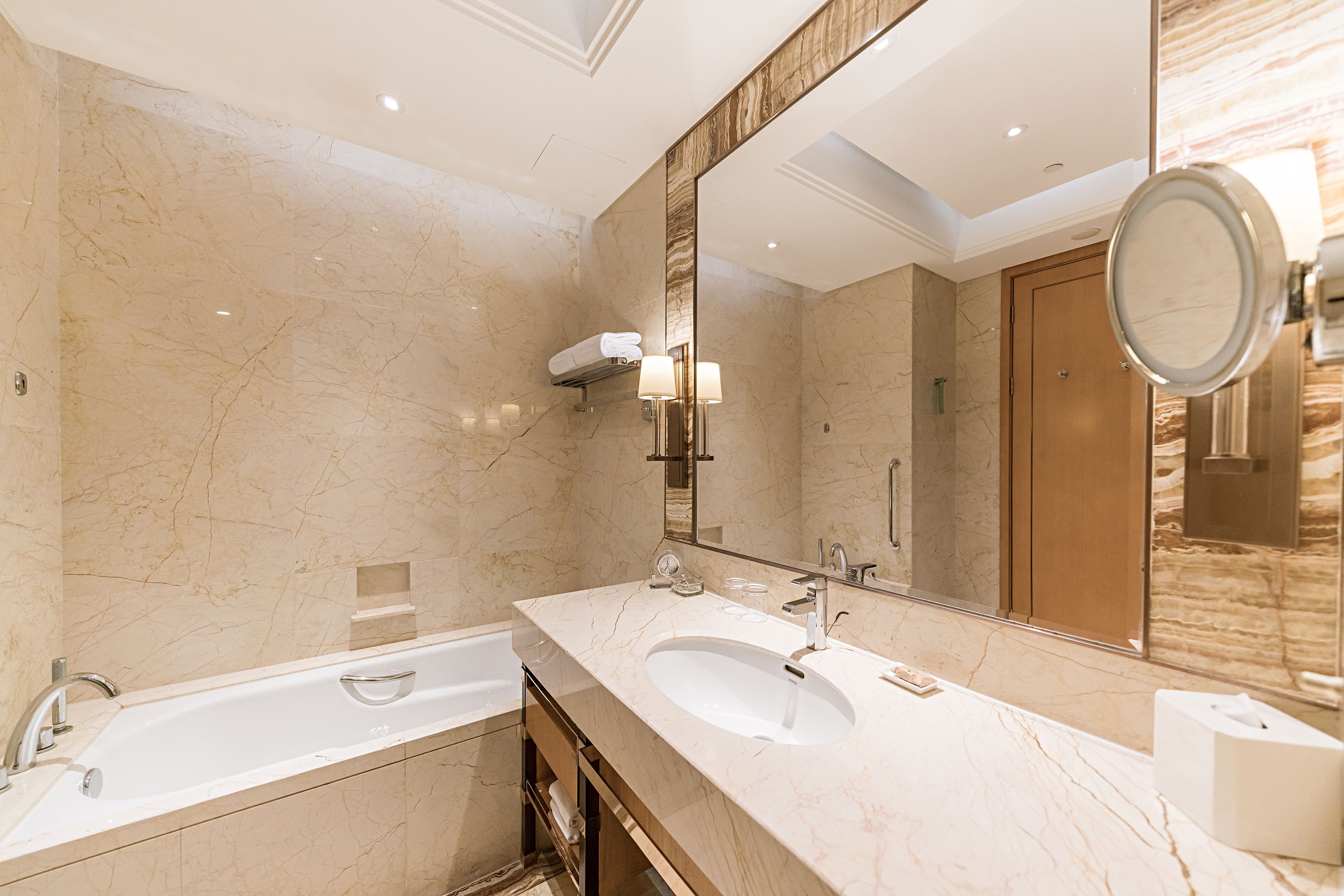A modern bathroom with a large mirror, two sinks, and a bathtub.