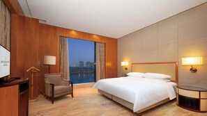 Habitación de hotel con una cama grande, un escritorio, una silla y vistas a la ciudad.