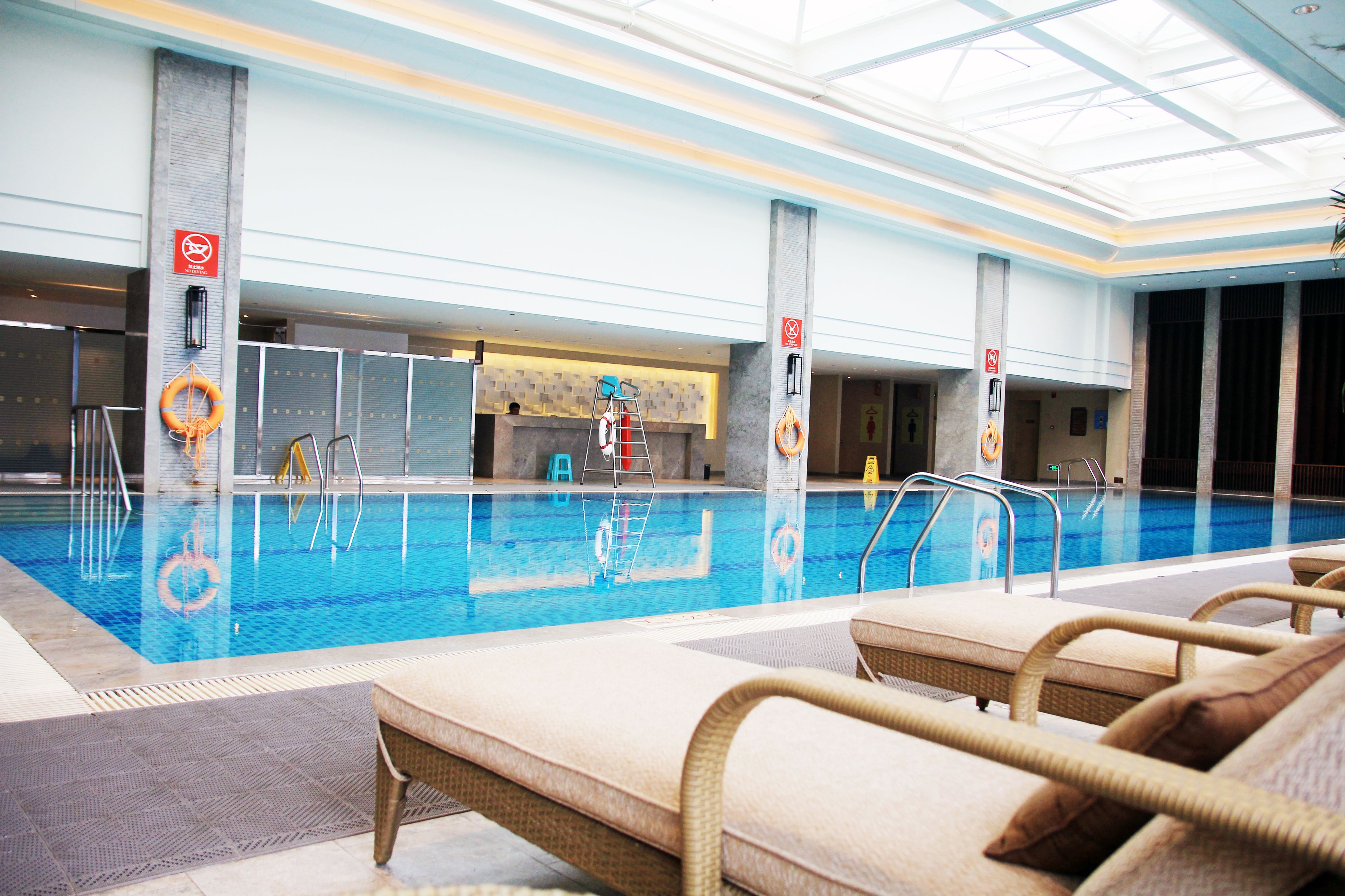 An indoor swimming pool with lounge chairs and safety equipment.