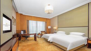 A hotel room with a large bed, a desk with a chair, a television, and a large window with curtains.