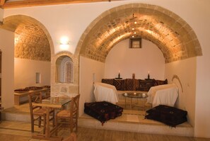 Una habitación acogedora con un arco de piedra, un comedor con mobiliario de madera y una pequeña mesa con velas.