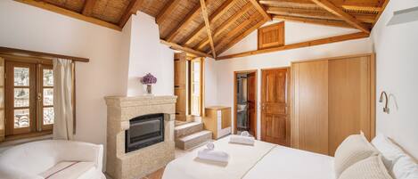 Un dormitorio con chimenea, vigas de madera en el techo, un sofá y una cama.
