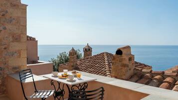 A terrace with a table set for breakfast overlooking the sea.