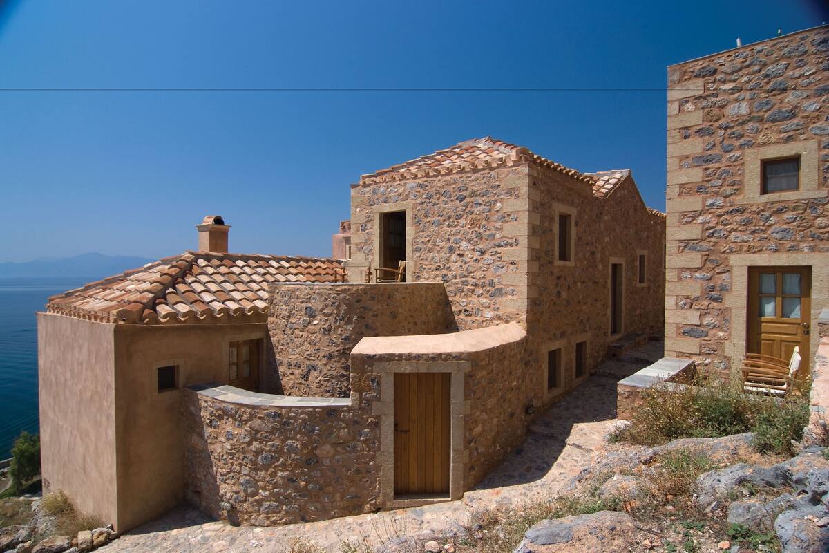 A stone building with a tiled roof, a wooden door, and a small window.