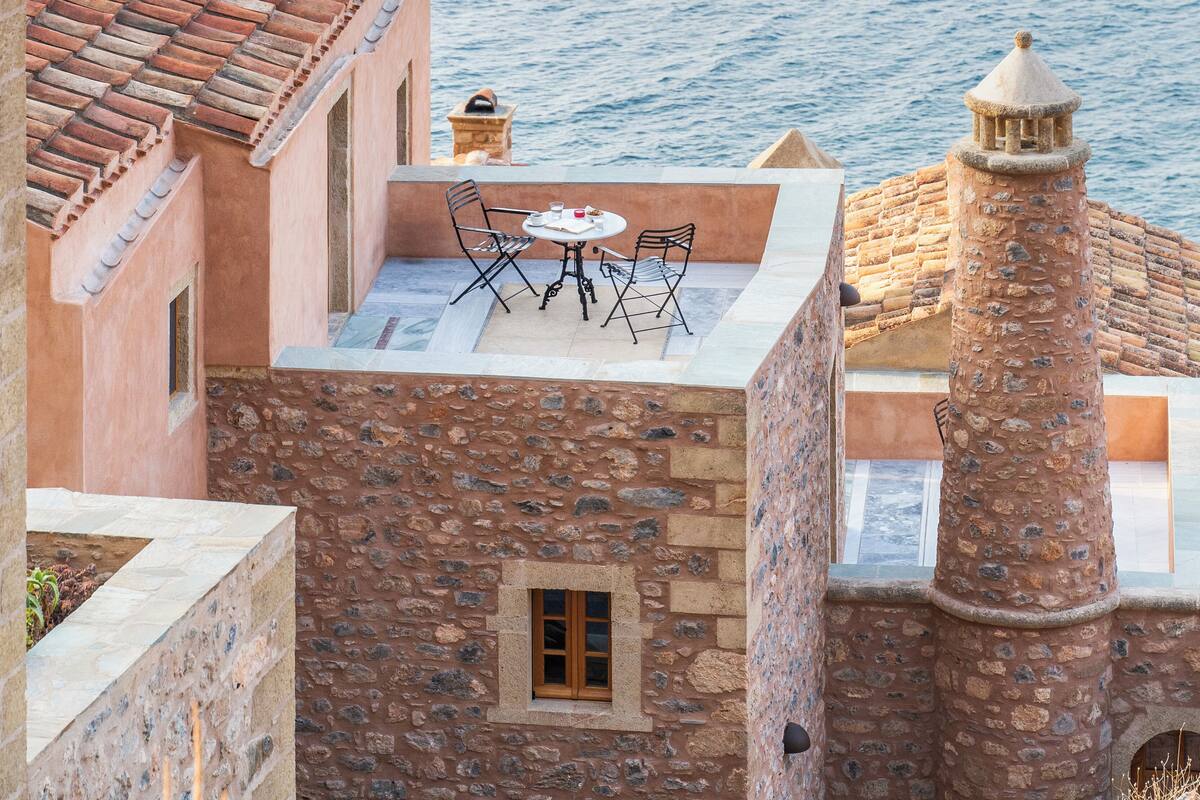 A rooftop terrace with a table and chairs, overlooking a body of water.