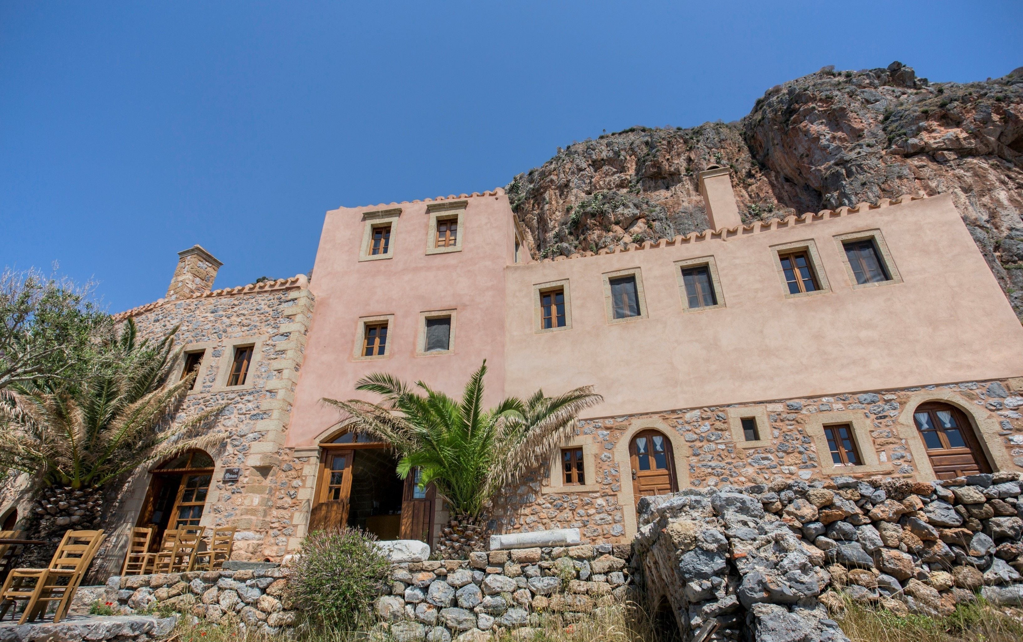 A stone building with multiple windows and a stone staircase leading to an entrance.