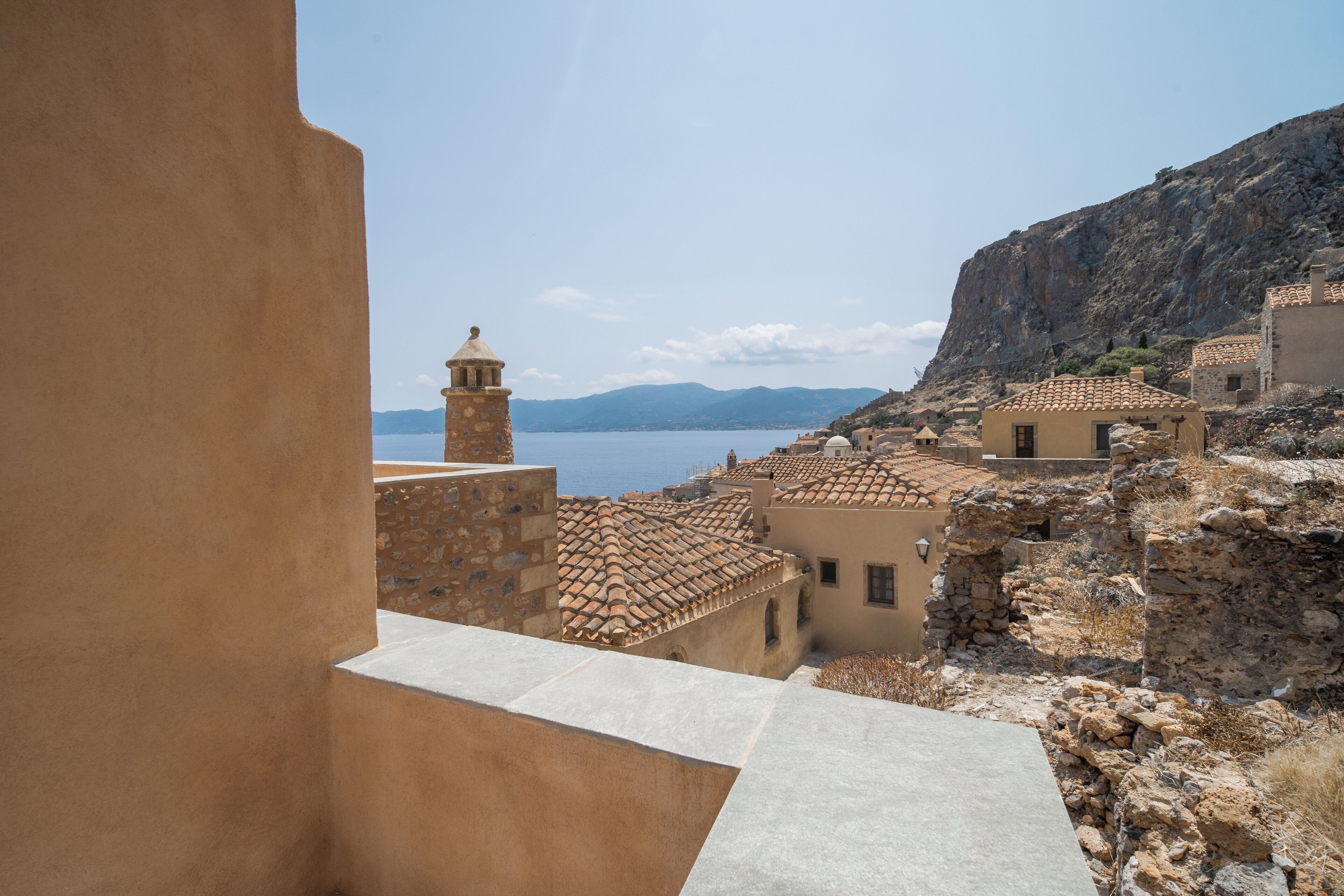 A coastal village with traditional architecture, including stone buildings and a bell tower, overlooking the sea.