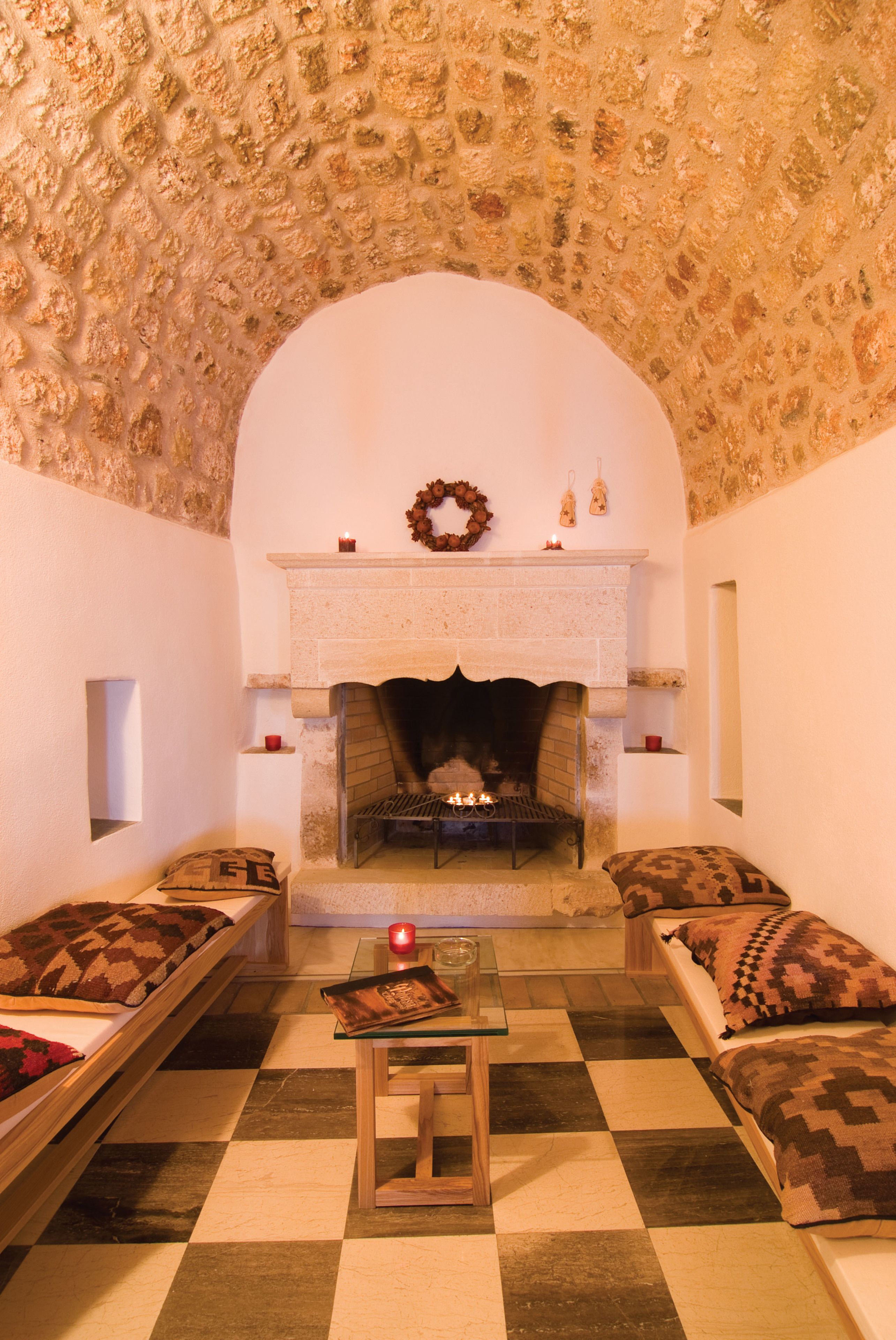 A cozy room with a checkered floor, a fireplace, and two sofas with patterned cushions.