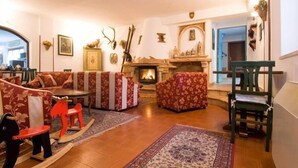 A cozy living room with a fireplace, floral-patterned sofas, a rocking horse, and a green chair. - LH Hotel Paradiso (Pescasseroli)