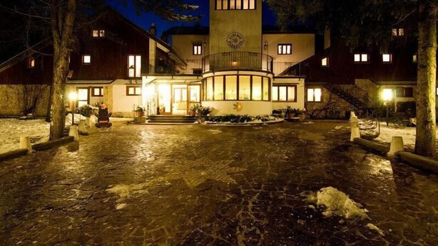 A hotel with a central courtyard, a clock tower, and multiple windows. - LH Hotel Paradiso (Pescasseroli)