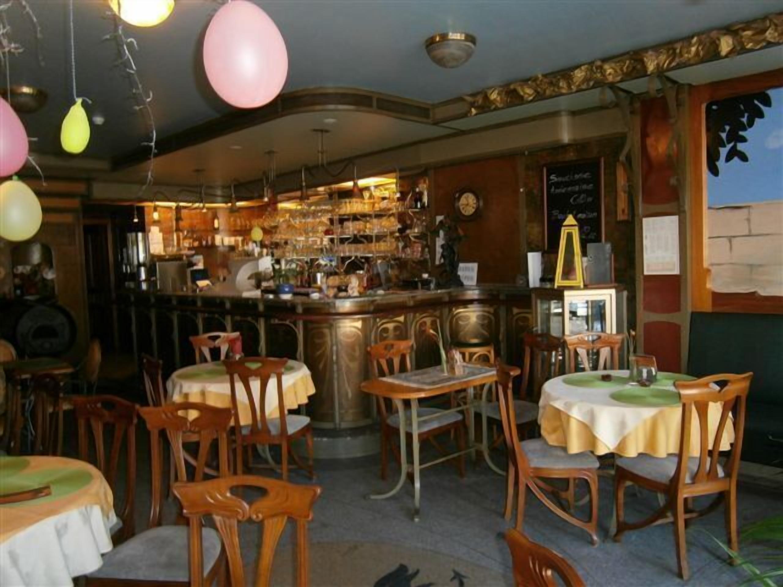 Een restaurant met houten stoelen en tafels, een bar met flessen en een menukaart op een schoolbord.