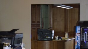 Zona de recepción con mostrador de madera, una máquina de café y una computadora.