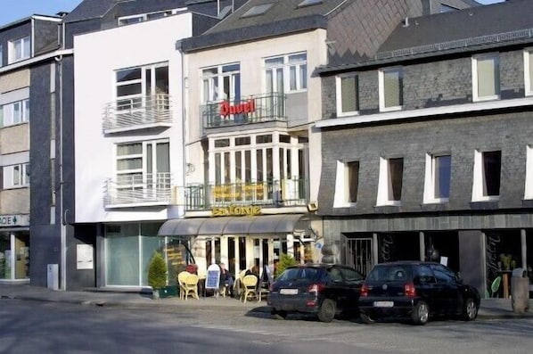 A hotel with a balcony, outdoor seating, and a sign that reads "Hotel".