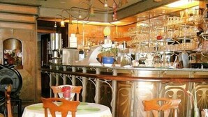 Zona de bar con mostrador de metal, luces colgantes y distintos utensilios.