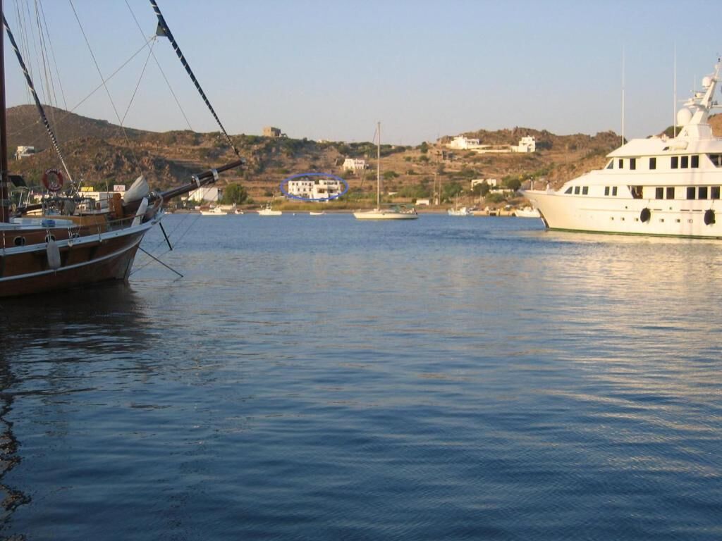 A marina with boats docked, a large yacht, and buildings in the background.