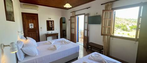 A hotel room with two beds, a wooden ceiling, a TV, and a window with a view.