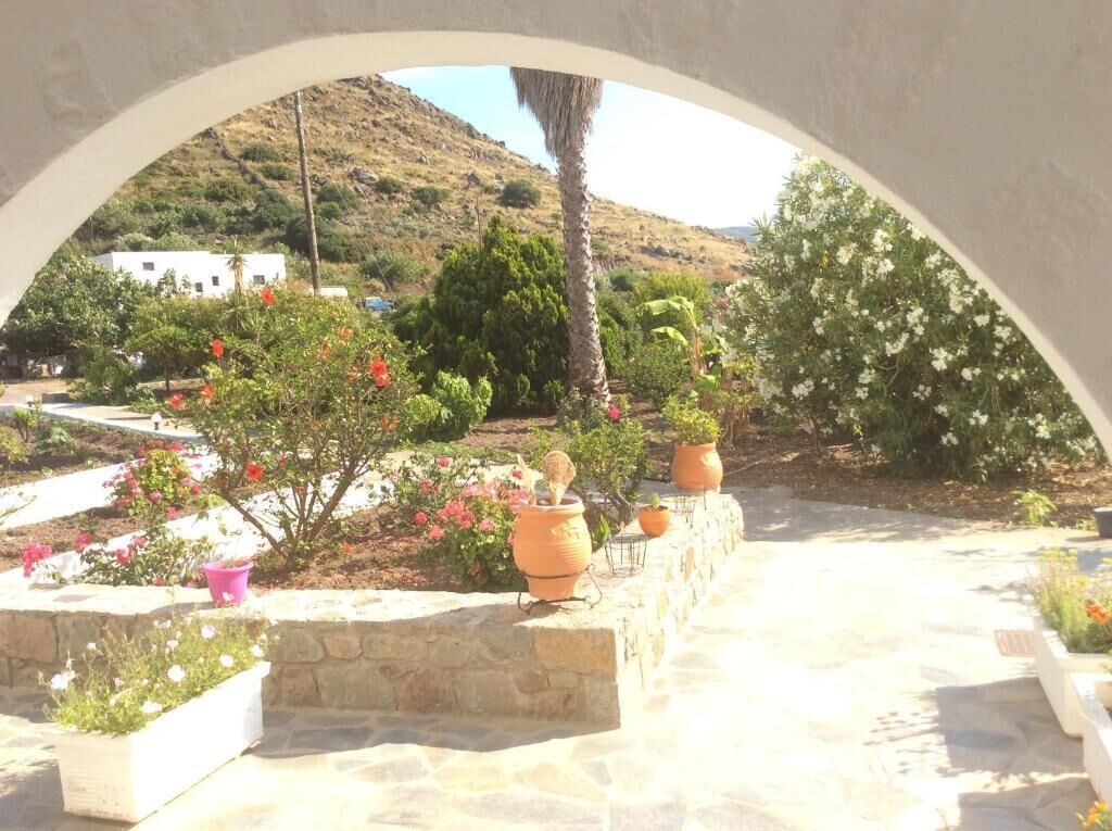 A stone pathway leading to a white building with a view of a hillside.