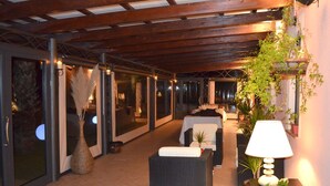 An indoor patio area with wicker furniture, a lamp, and potted plants.