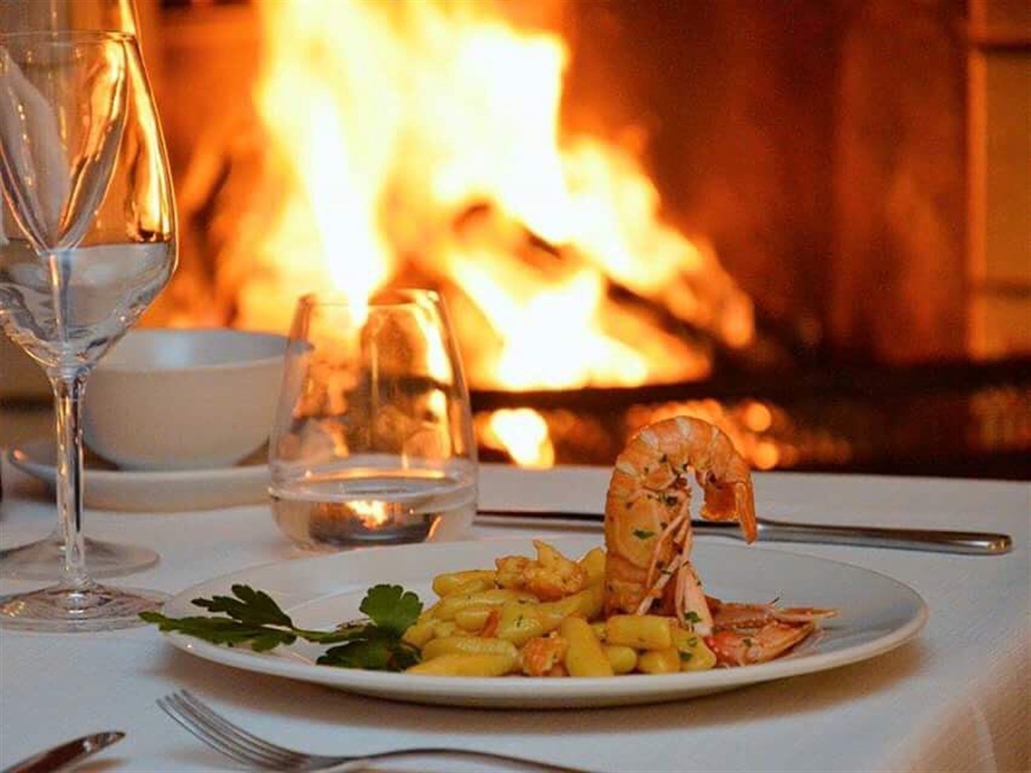A dining table with a plate of food, a glass of water, and a glass of wine.