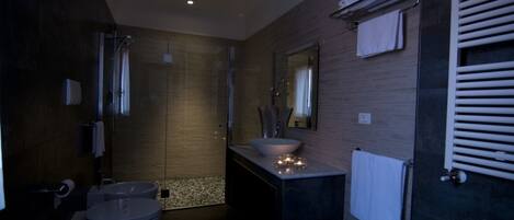 A modern bathroom with a glass-enclosed shower, a large sink, and a towel rack.