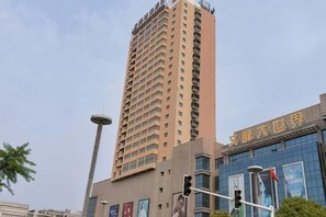 Ein hohes Gebäude mit modernem Design, das auf der linken Seite eine markante vertikale Struktur aufweist.