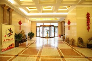 Un vestíbulo de hotel con piso de mármol, puerta giratoria y mostrador de recepción.