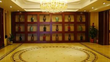 A lobby with a circular patterned floor, a chandelier, and a wall of vases.