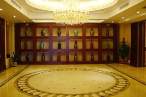 Un vestíbulo con piso de diseño circular, un candelabro y una pared de jarrones.