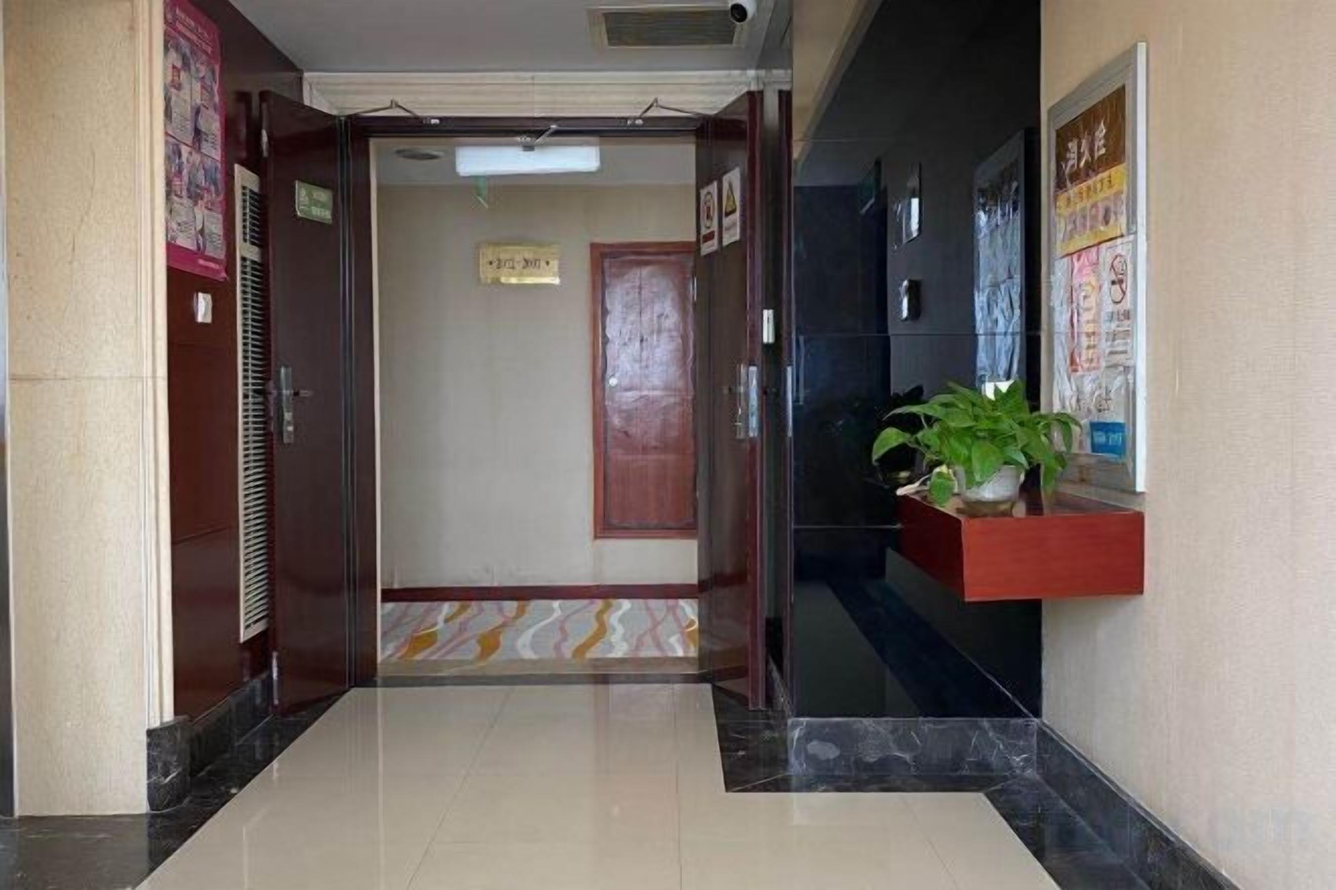 Un vestíbulo de hotel con una recepción, una planta en maceta y un cartel en la pared.