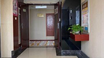 Un vestíbulo de hotel con una recepción, una planta en maceta y un cartel en la pared.
