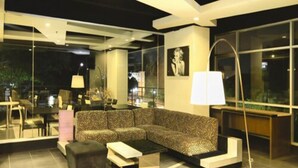 Una sala moderna con un sofá seccional, una mesa de centro y una lámpara de pie. Cuenta con un muro de vidrio con vistas al exterior.
