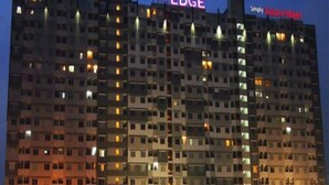 Un hotel de varios pisos con ventanas e balcones iluminados, llamado "The Edge" y "Simply Value Hotel".