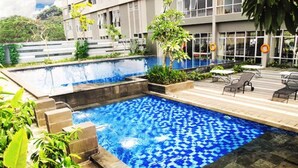 Una piscina con un diseño azul de mosaicos, rodeada por un suelo de piedra y plantas en macetas.