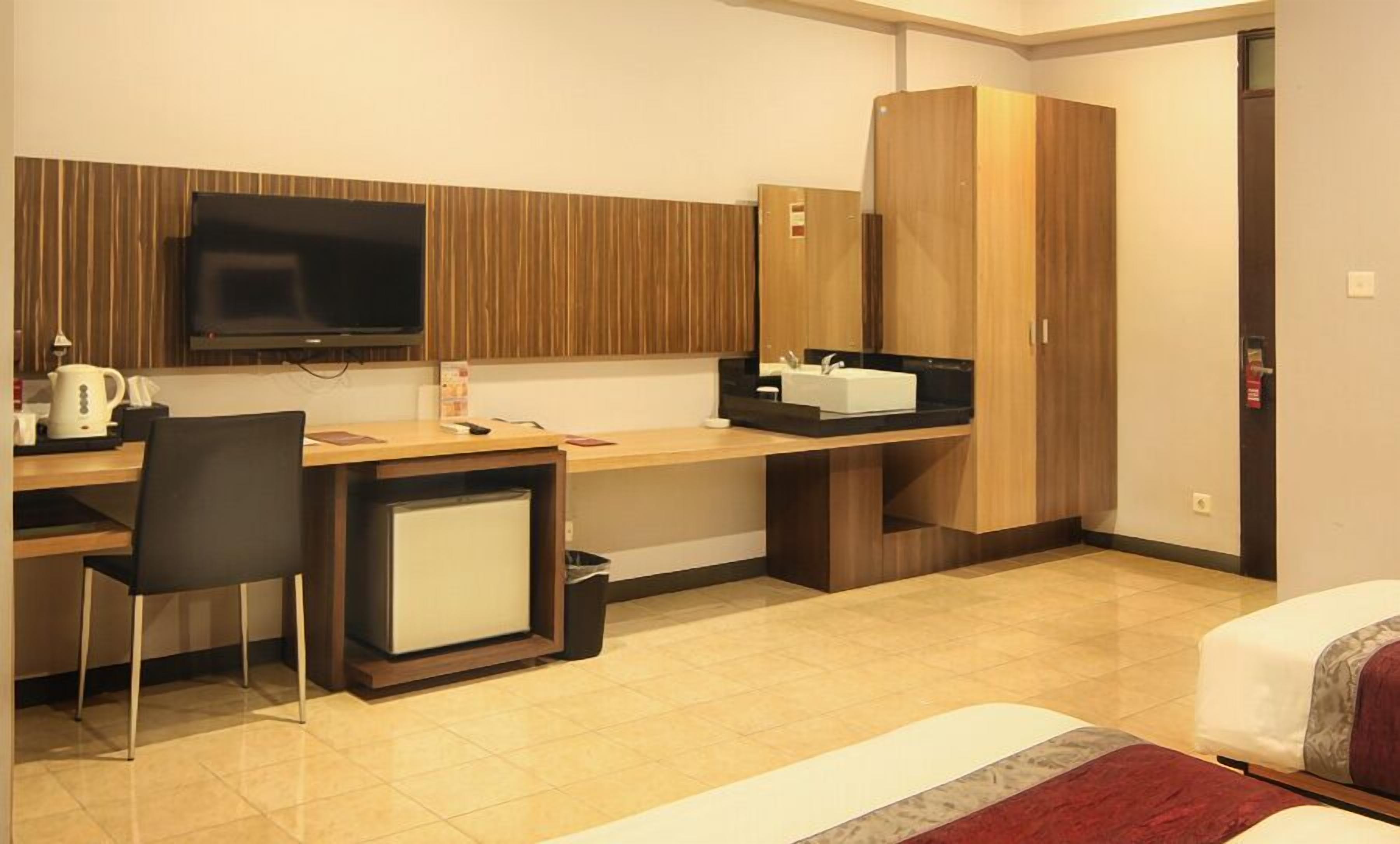 Une chambre d’hôtel comprenant un lit, un bureau avec un ordinateur, une télévision et une armoire.