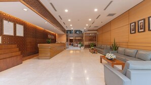 Un amplio vestíbulo con mostrador de recepción, zona de estar y paneles decorativos.