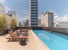 Una piscina al aire libre, sombrillas, sillones reclinables de piscina