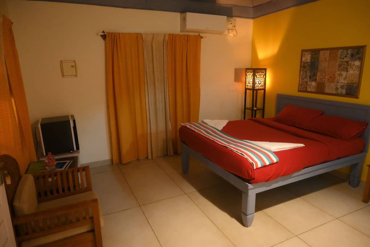 A bedroom with a bed, curtains, a TV, and a lamp.