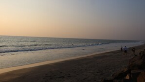 A beach with people walking along the shore. - Magnolia Guest House (Varkala)
